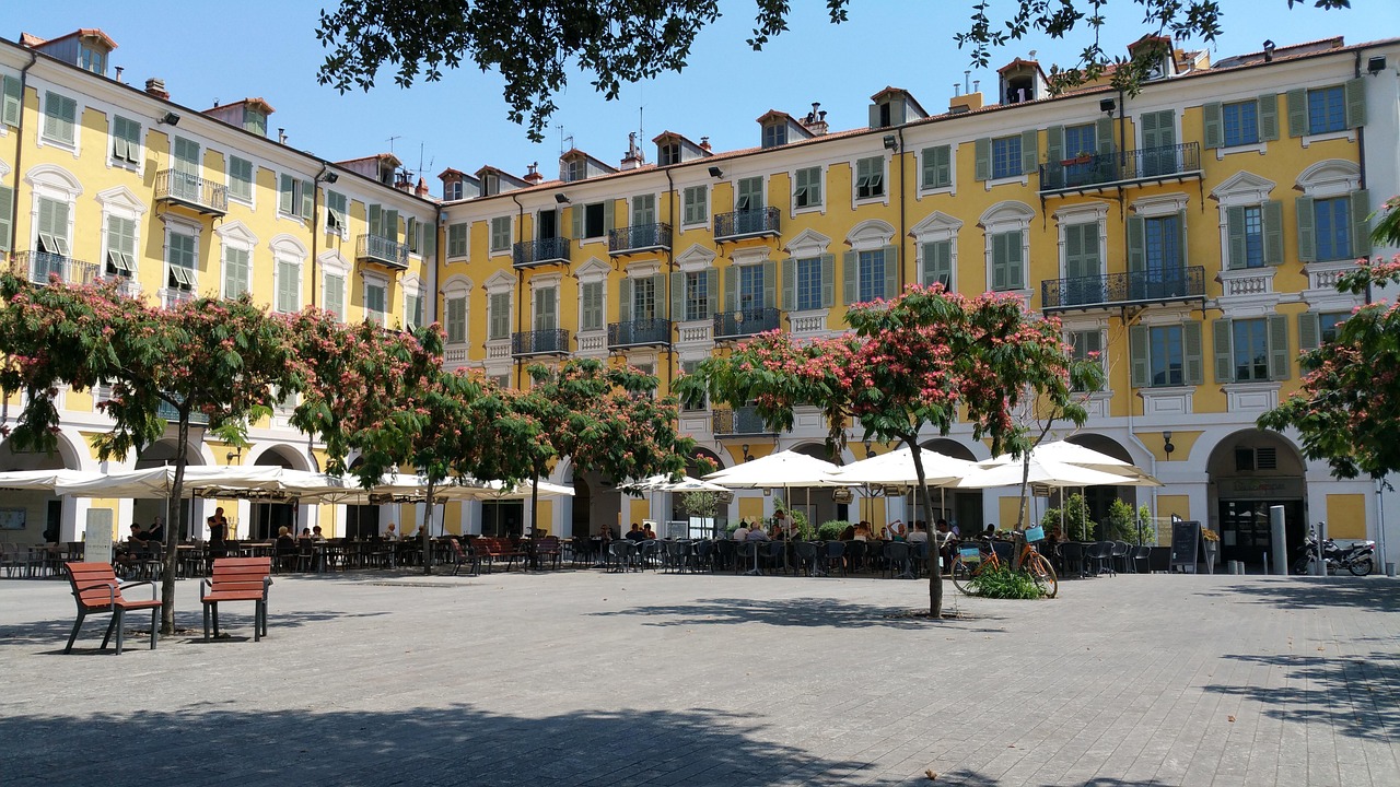 Piazza tranquilla in un borgo storico, circondata da edifici antichi e fiori colorati.