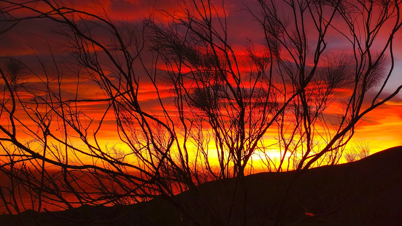 Tramonto colorato sulla valle, con nuvole rosa e arancioni che si riflettono nel paesaggio.