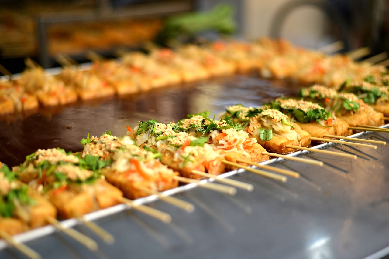 Un venditore di street food locale mentre prepara piatti tipici in un mercato affollato.