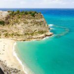 Spiaggia nascosta in Italia, sabbia dorata e mare cristallino, ideale per una fuga estiva tranquilla.