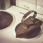 Ferro da stiro con vapore, vicino a una bottiglia di aceto per rimuovere il calcare.