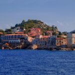 Vista panoramica del borgo di Isola del Giglio con spiagge e mare cristallino.
