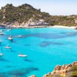 Caletta cristallina in Sardegna, circondata da rocce e vegetazione mediterranea, un vero paradiso nascosto.