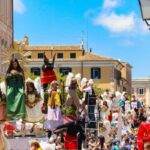 Folla festante durante una celebrazione di una festa patronale italiana, con colori vivaci e tradizioni locali.