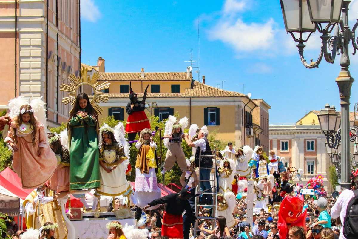 Folla festante durante una celebrazione di una festa patronale italiana, con colori vivaci e tradizioni locali.