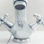 Rubinetto che perde acqua con attrezzi per riparazione sul tavolo.