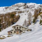 Rifugio di montagna panoramico in Italia circondato da vette e boschi verdi.